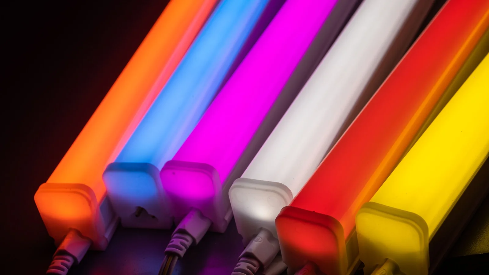 Row of glowing LED tube lights in orange, blue, pink, white, red and yellow