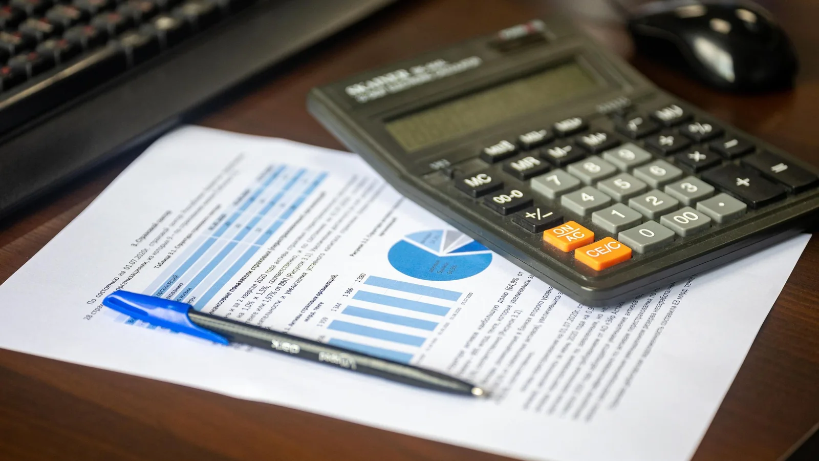 A calculator, pen and financial report on a desk