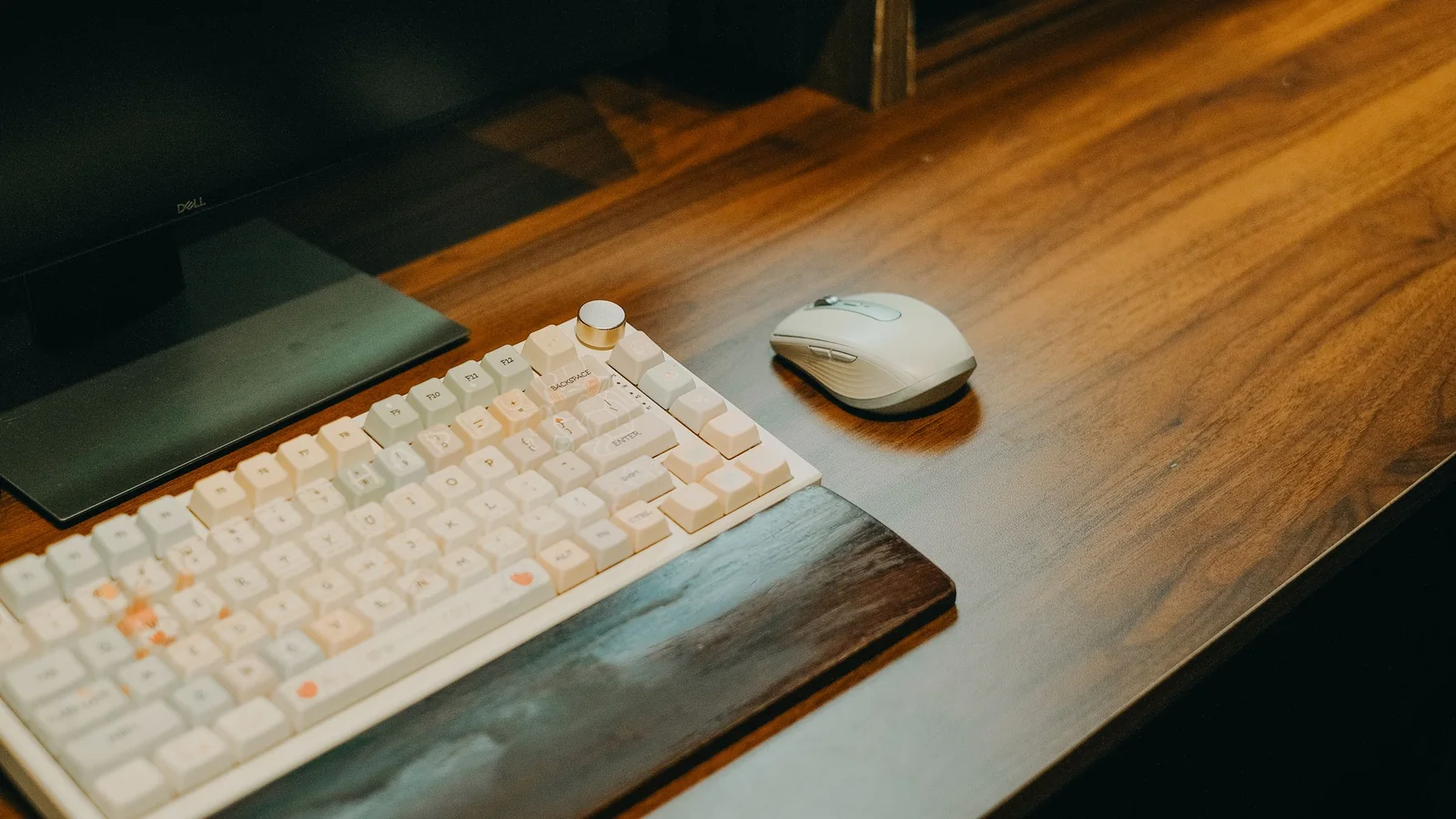 A minimalist wooden desk with a keyboard, mouse and monitor
