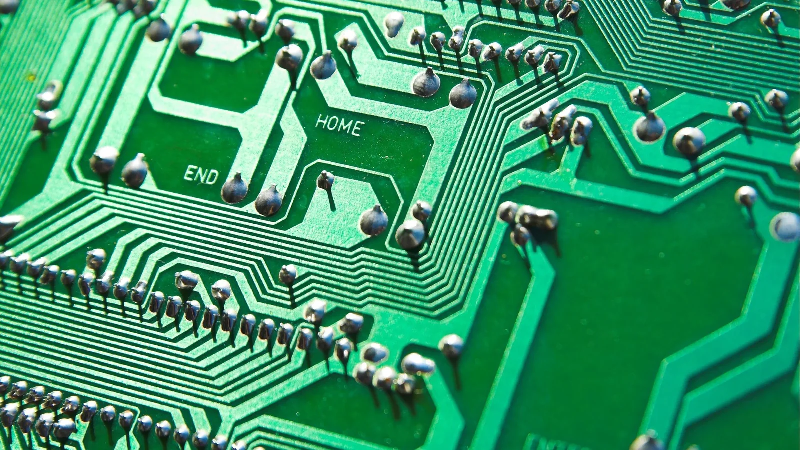 Close-up of a green printed circuit board with traces and components