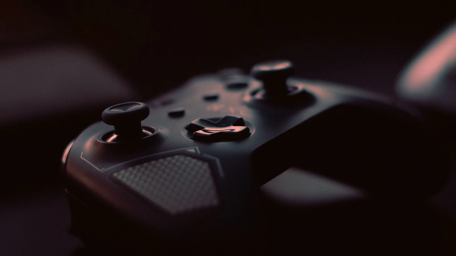 A dark game controller lit by low, moody light