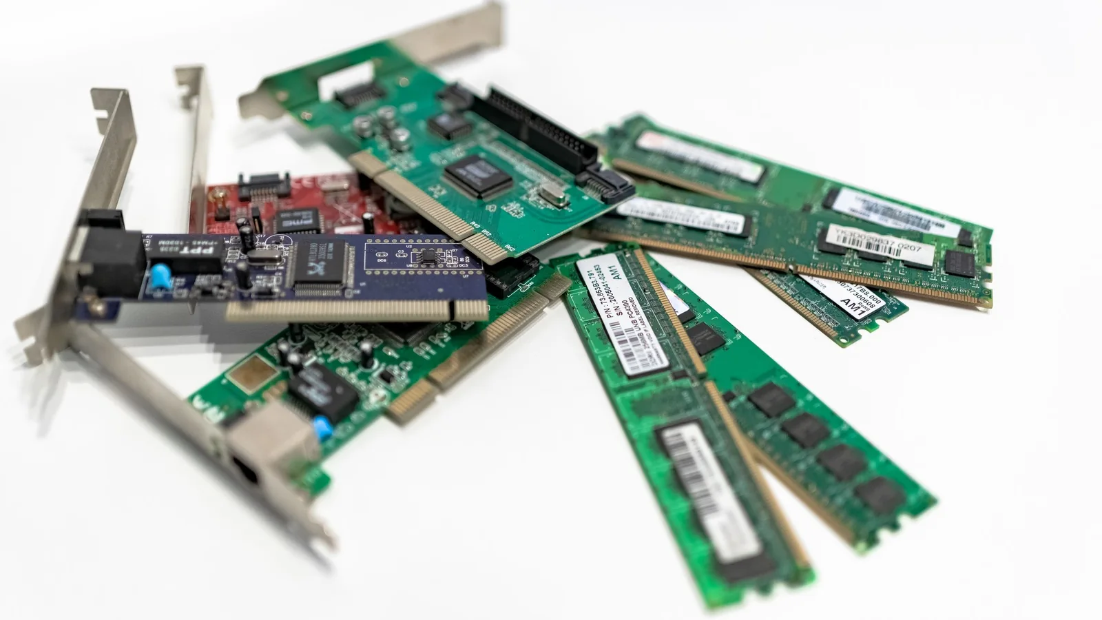 Computer RAM sticks and expansion cards piled on a white surface